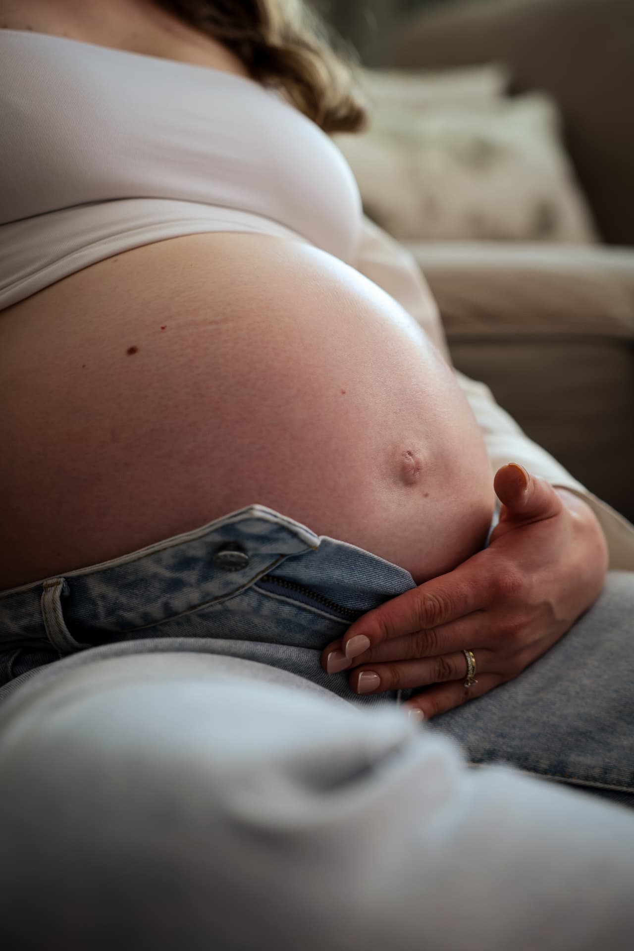 Nahaufnahme eines Babybauchs über einer Jeanshose