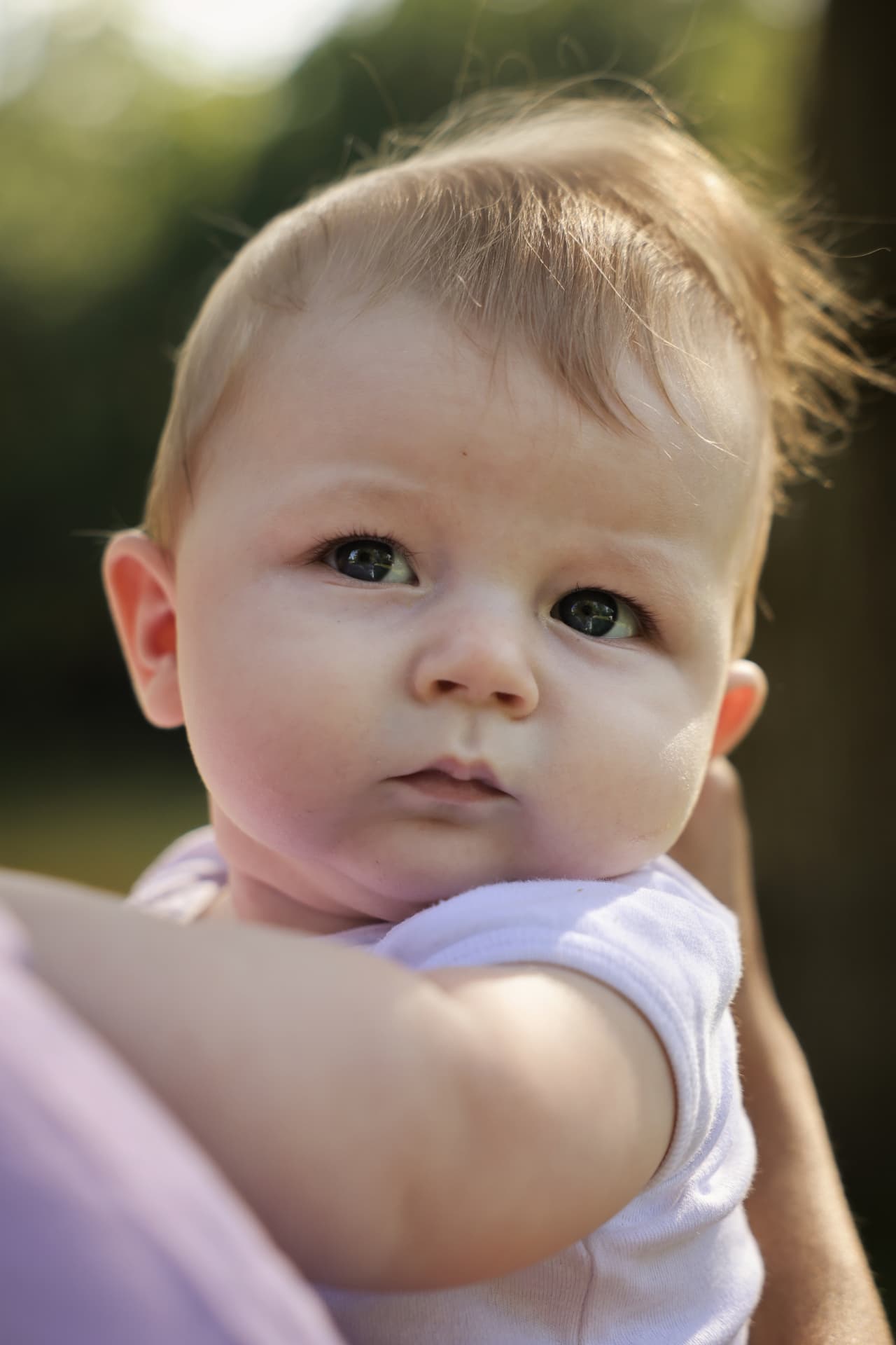 Hochformat-Porträt eines Babys mit hellen Augen im warmen Abendlicht