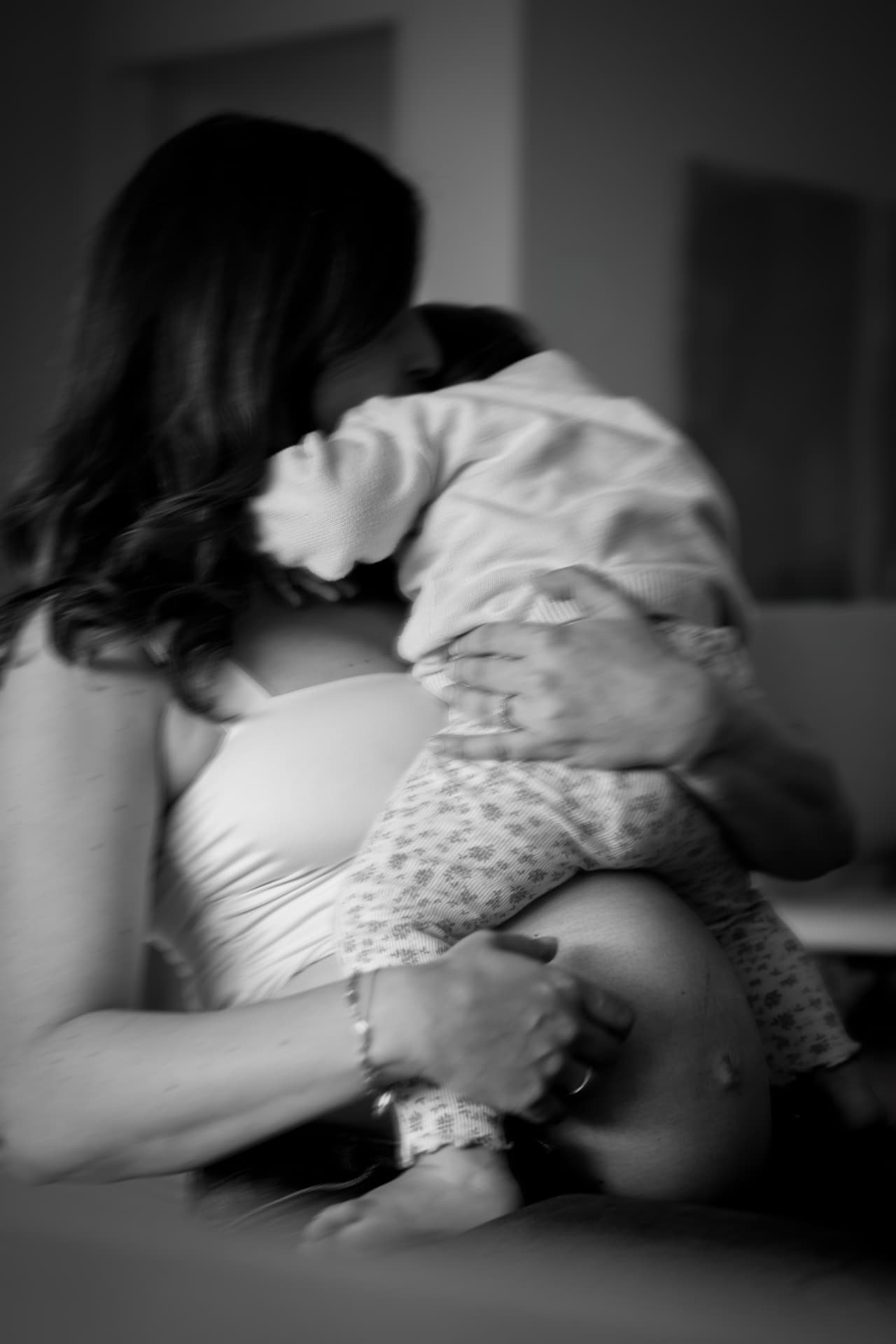 Schwarzweiß-Aufnahme: Mutter kuschelt mit ihrem Kind auf dem Babybauch