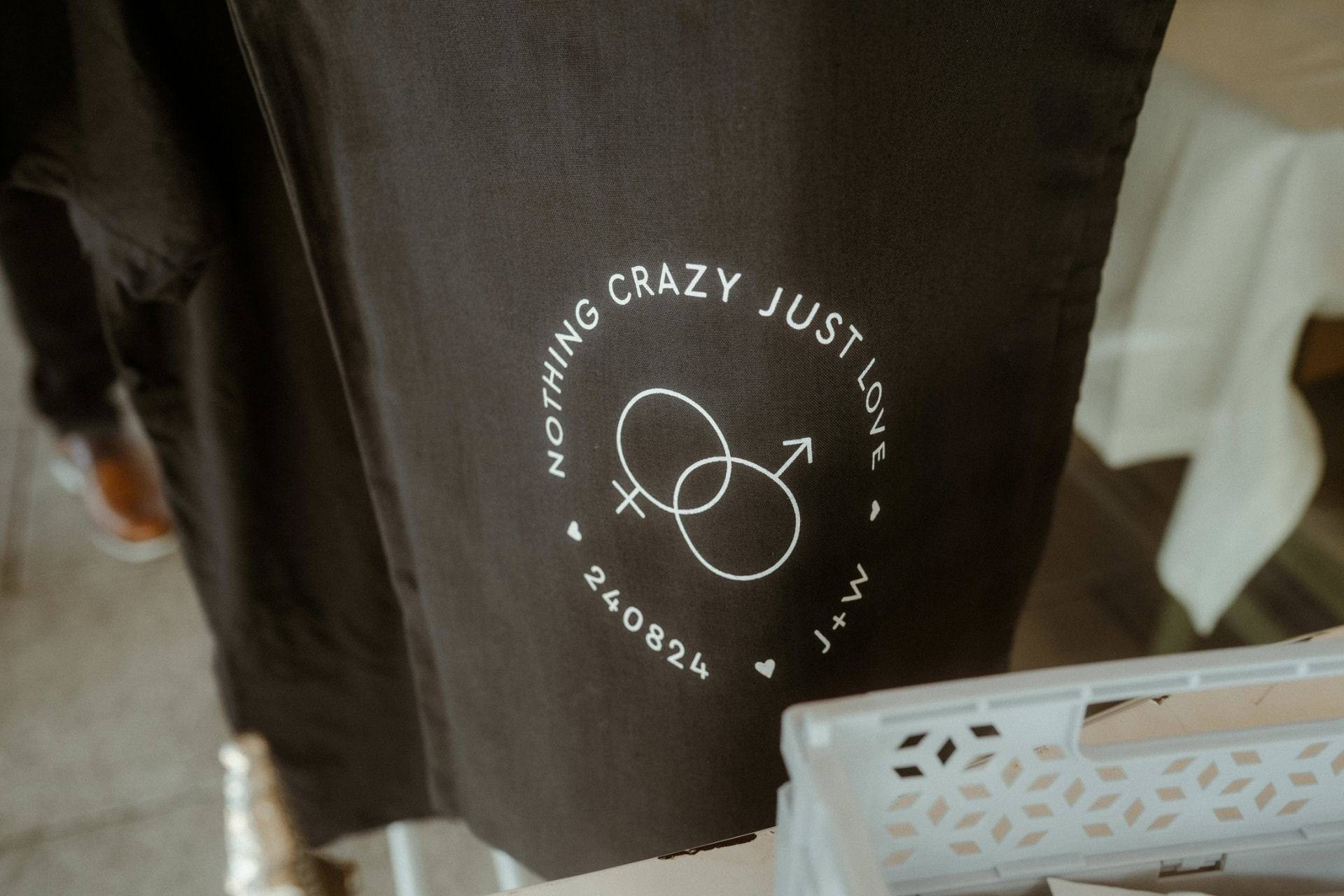 Schwarzes Textil mit weißem Rundlogo Nothing crazy just love und dem Datum 240824