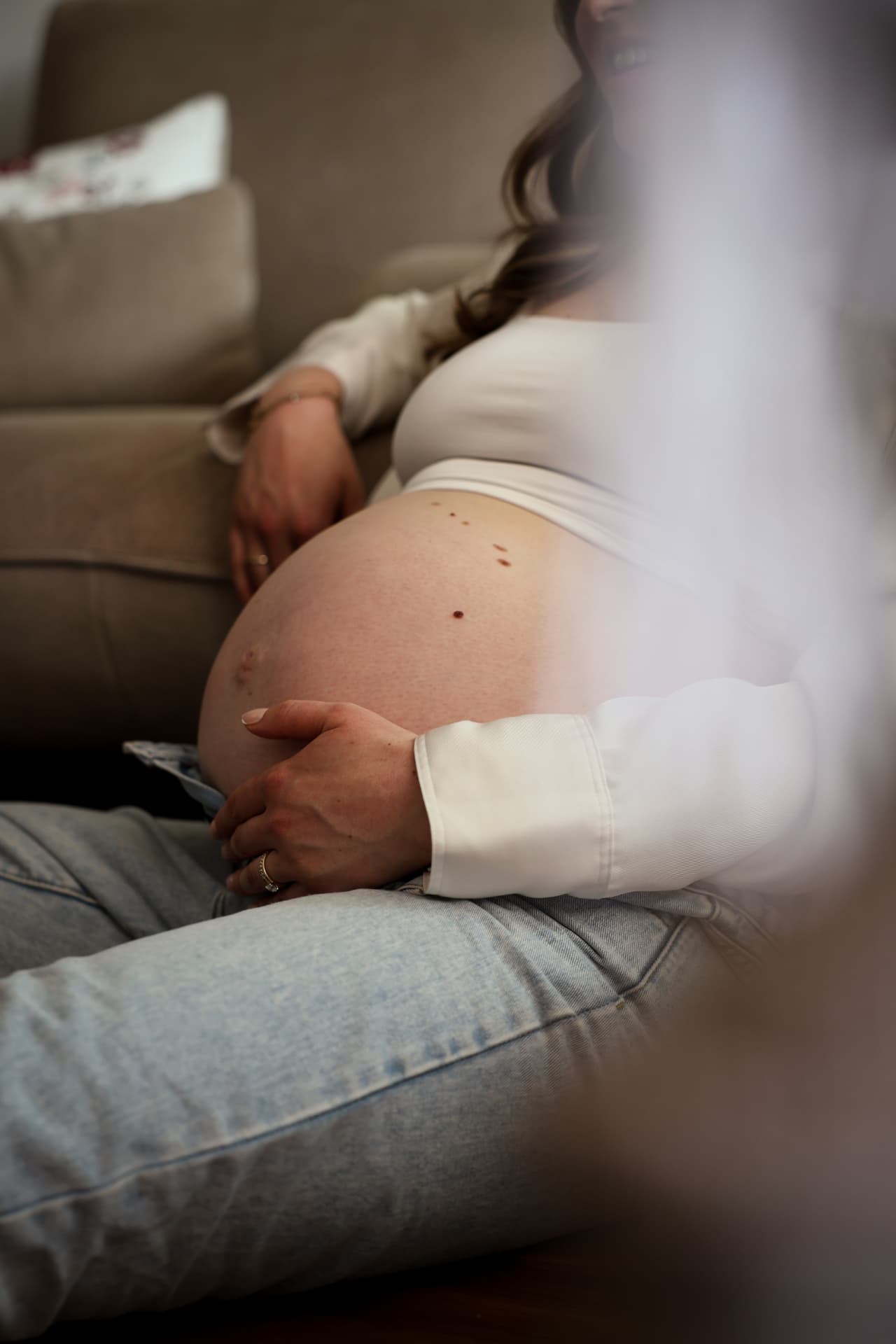 Schwangere mit Zöpfen liegt entspannt auf dem Sofa